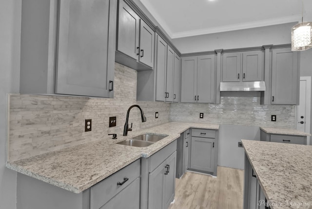 kitchen with decorative light fixtures, ornamental molding, sink, and tasteful backsplash