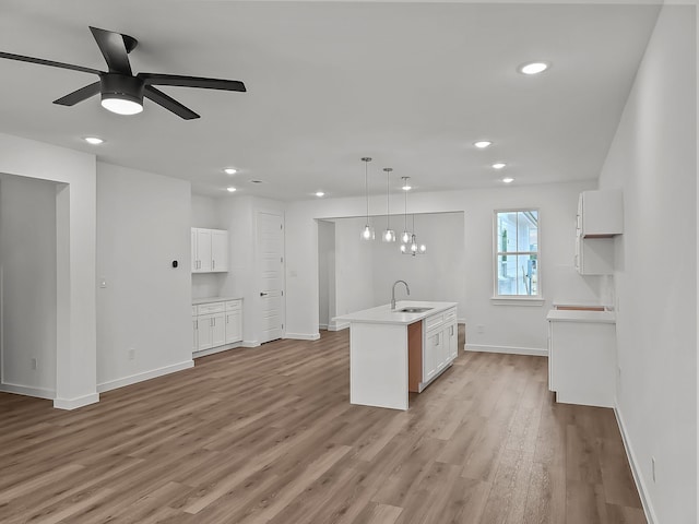 kitchen featuring white cabinets, a center island with sink, pendant lighting, and sink