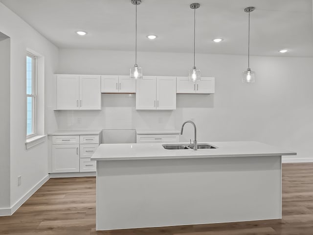 kitchen featuring sink, white cabinetry, decorative light fixtures, and a kitchen island with sink