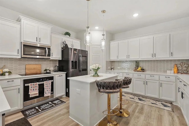 kitchen featuring pendant lighting, a center island, tasteful backsplash, white cabinetry, and stainless steel appliances