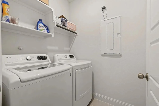 clothes washing area with washing machine and dryer, electric panel, and light tile patterned flooring