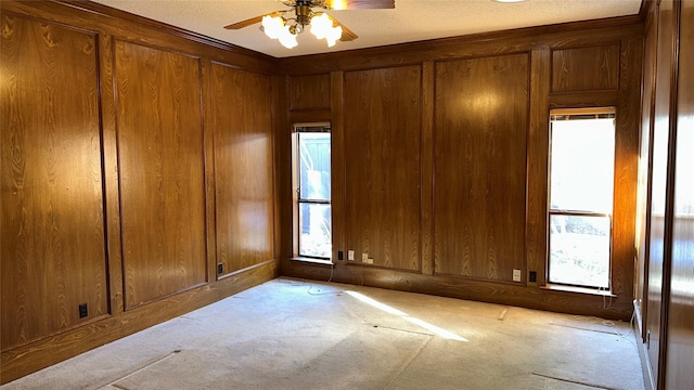 carpeted spare room featuring ceiling fan and wooden walls