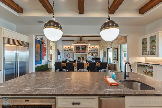 kitchen featuring sink, hanging light fixtures, built in fridge, and white cabinets