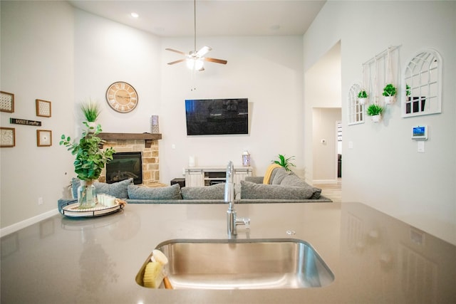 kitchen with a stone fireplace, ceiling fan, and sink