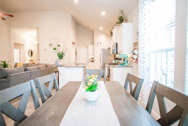 dining space featuring ceiling fan, sink, and high vaulted ceiling