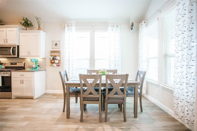 dining area featuring vaulted ceiling and light hardwood / wood-style flooring