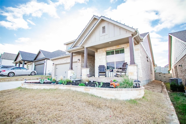 view of front facade featuring a porch, a garage, a front yard, and central AC