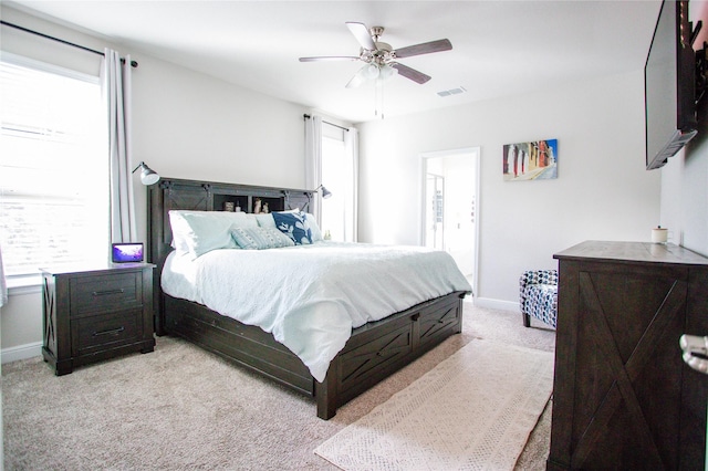 carpeted bedroom featuring ceiling fan, ensuite bath, and multiple windows