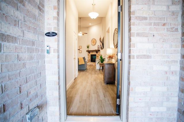 hallway with light hardwood / wood-style floors and brick wall