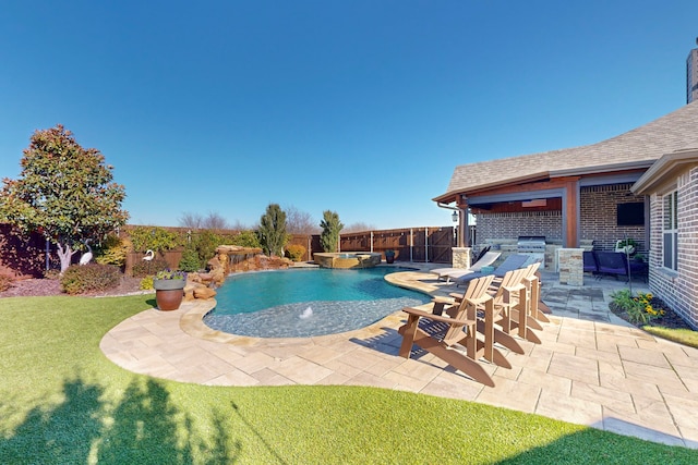 view of swimming pool with a lawn, a patio area, pool water feature, and exterior kitchen