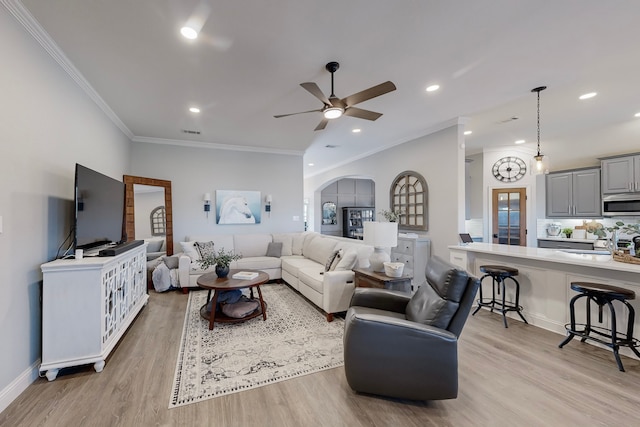 living room featuring crown molding, light hardwood / wood-style flooring, ceiling fan, and sink