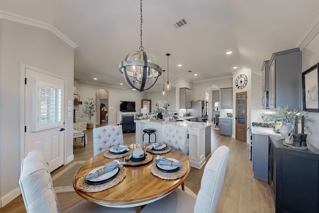 dining room with light hardwood / wood-style floors, an inviting chandelier, and ornamental molding