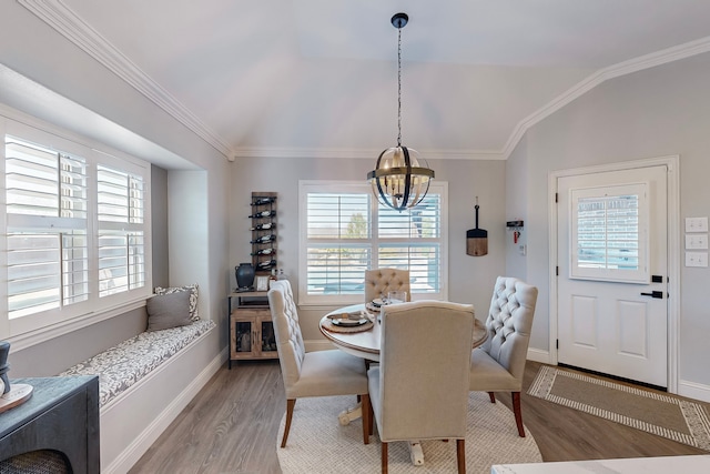 dining area featuring a chandelier, crown molding, light hardwood / wood-style floors, and vaulted ceiling