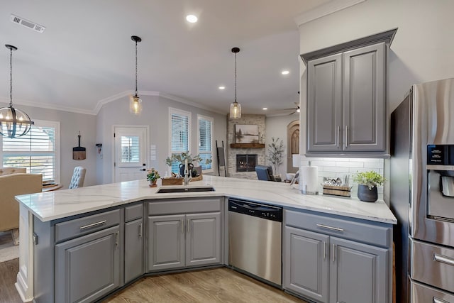 kitchen with sink, stainless steel appliances, pendant lighting, gray cabinets, and a fireplace