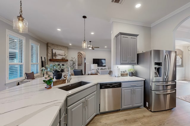 kitchen featuring ceiling fan, sink, stainless steel appliances, a stone fireplace, and gray cabinets