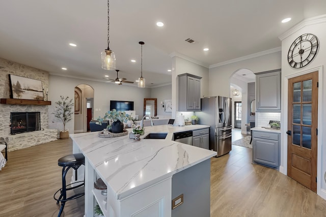 kitchen with light stone countertops, gray cabinetry, stainless steel appliances, sink, and a fireplace