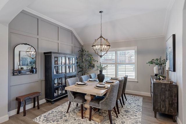 dining area featuring crown molding, wood-type flooring, vaulted ceiling, and an inviting chandelier