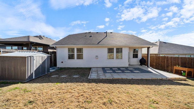 rear view of house with a yard, a patio, and a storage unit