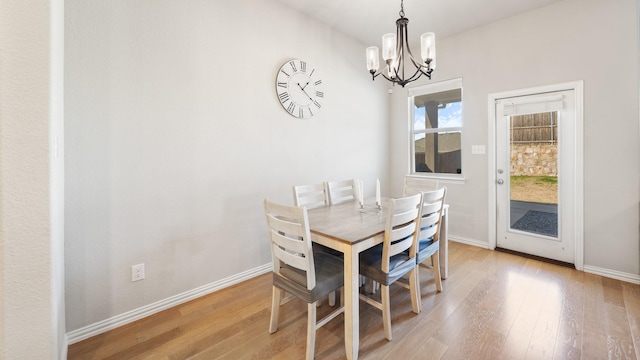 dining space with light wood-type flooring and an inviting chandelier