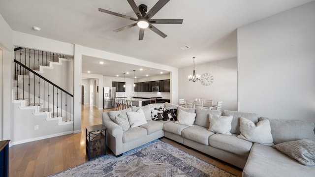 living room featuring hardwood / wood-style floors, ceiling fan with notable chandelier, and sink