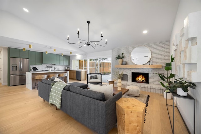 living room featuring lofted ceiling, a fireplace, light wood-type flooring, and a notable chandelier