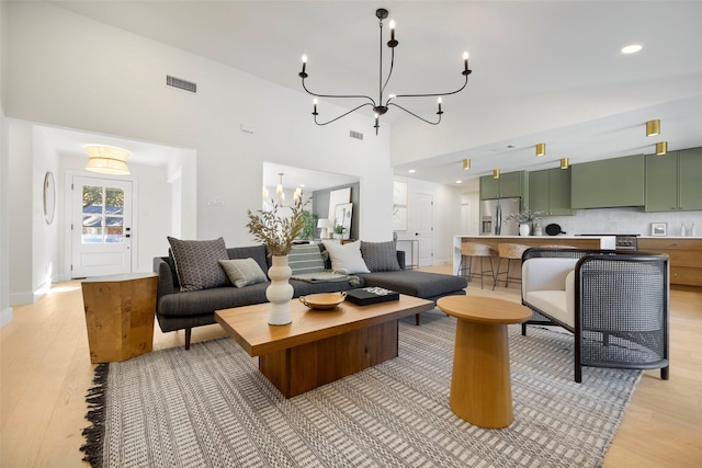 living room featuring hardwood / wood-style floors, vaulted ceiling, and a notable chandelier