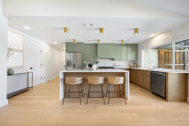 kitchen featuring sink, stainless steel appliances, a center island, and a kitchen bar