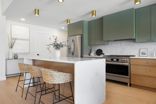 kitchen featuring appliances with stainless steel finishes, tasteful backsplash, wall chimney exhaust hood, and green cabinets