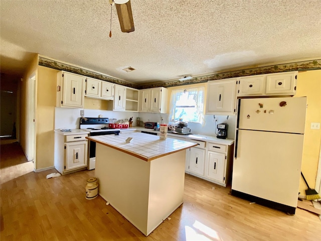 kitchen with tile counters, light hardwood / wood-style flooring, electric range, white cabinets, and white refrigerator