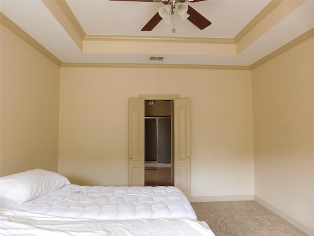 carpeted bedroom featuring ceiling fan, ornamental molding, and a tray ceiling