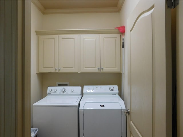 laundry room with washing machine and dryer, crown molding, and cabinets