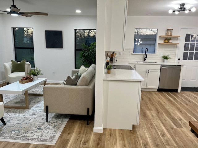 living room featuring sink, ceiling fan with notable chandelier, and light wood-type flooring