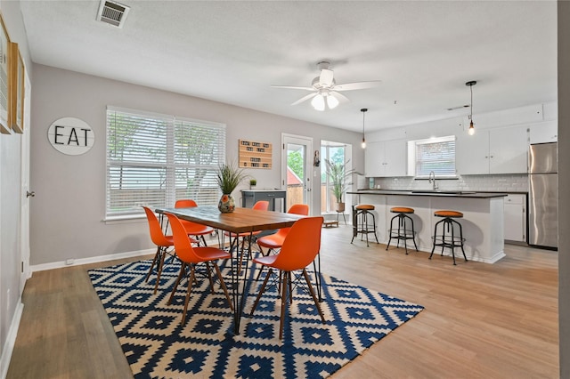 dining space with a wealth of natural light, ceiling fan, sink, and light hardwood / wood-style floors