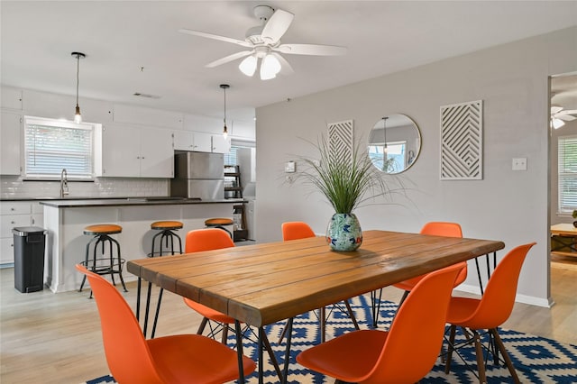 dining space featuring ceiling fan, light wood-type flooring, and sink