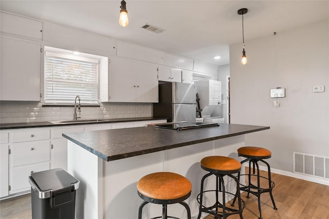 kitchen with stainless steel fridge, sink, white cabinets, and a kitchen island