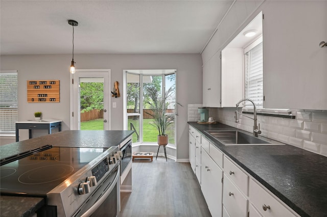 kitchen with tasteful backsplash, white cabinetry, sink, and stainless steel range with electric stovetop