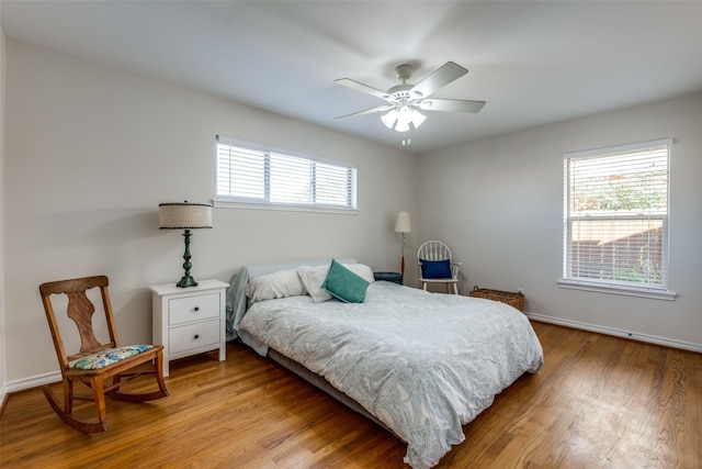 bedroom featuring ceiling fan, multiple windows, and light hardwood / wood-style flooring