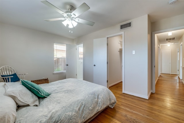 bedroom with a spacious closet, ceiling fan, a closet, and light hardwood / wood-style flooring