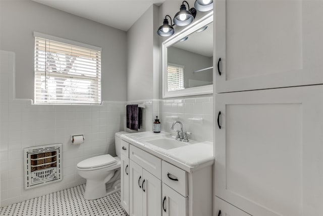 bathroom with tile walls, toilet, heating unit, and vanity