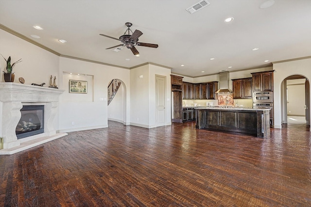 unfurnished living room with ceiling fan, crown molding, and dark hardwood / wood-style floors