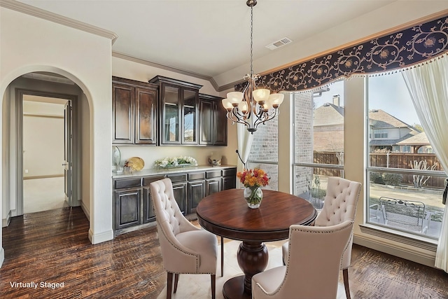 dining space featuring ornamental molding, dark wood-type flooring, and an inviting chandelier