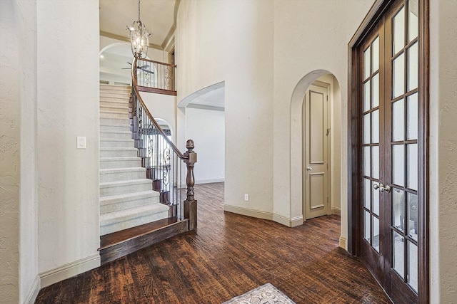 entrance foyer with french doors, a chandelier, crown molding, and dark hardwood / wood-style floors