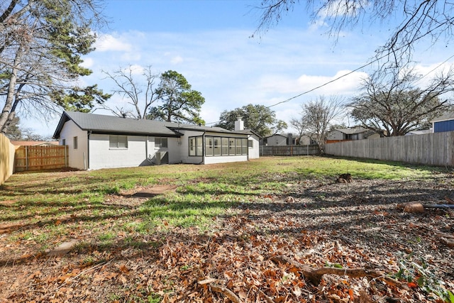 back of property with a lawn and a sunroom