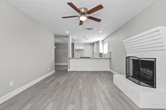 unfurnished living room with ceiling fan, a fireplace, and light hardwood / wood-style flooring