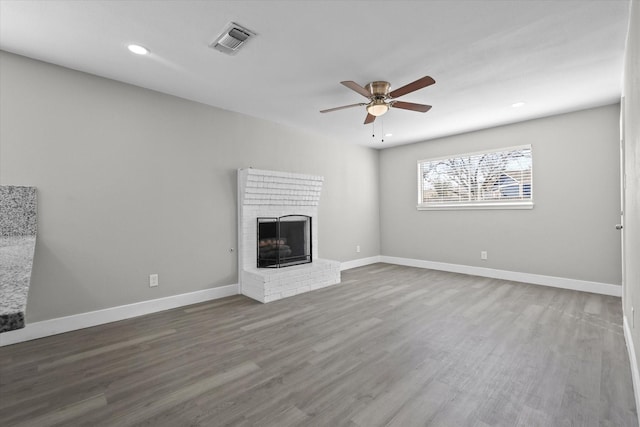 unfurnished living room with ceiling fan, a fireplace, and wood-type flooring