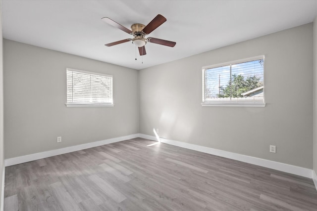 empty room with light hardwood / wood-style floors, a wealth of natural light, and ceiling fan