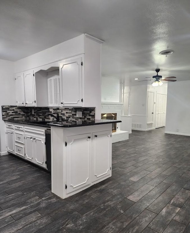 1911 College St, Gainesville, TX 76240 - kitchen with dark countertops, ceiling fan, white cabinets, backsplash, and a sink