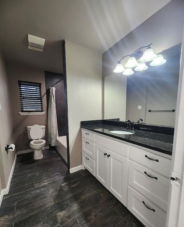 1911 College St, Gainesville, TX 76240 - full bathroom with toilet, vanity, baseboards, and wood finished floors