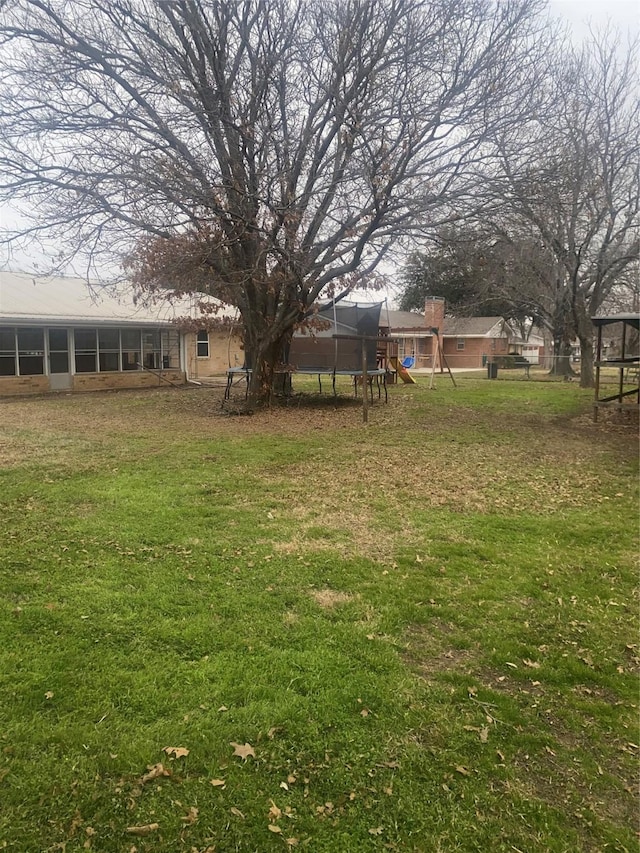 1911 College St, Gainesville, TX 76240 - view of grassy yard featuring a playground, a sunroom, and a trampoline