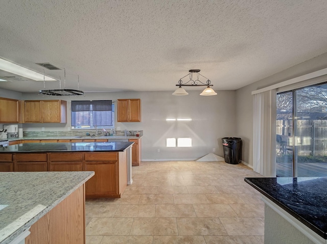 kitchen featuring sink, plenty of natural light, dark stone counters, and decorative light fixtures